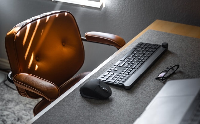 パソコンのキーボードとマウスが置かれたデスクと革張りの椅子